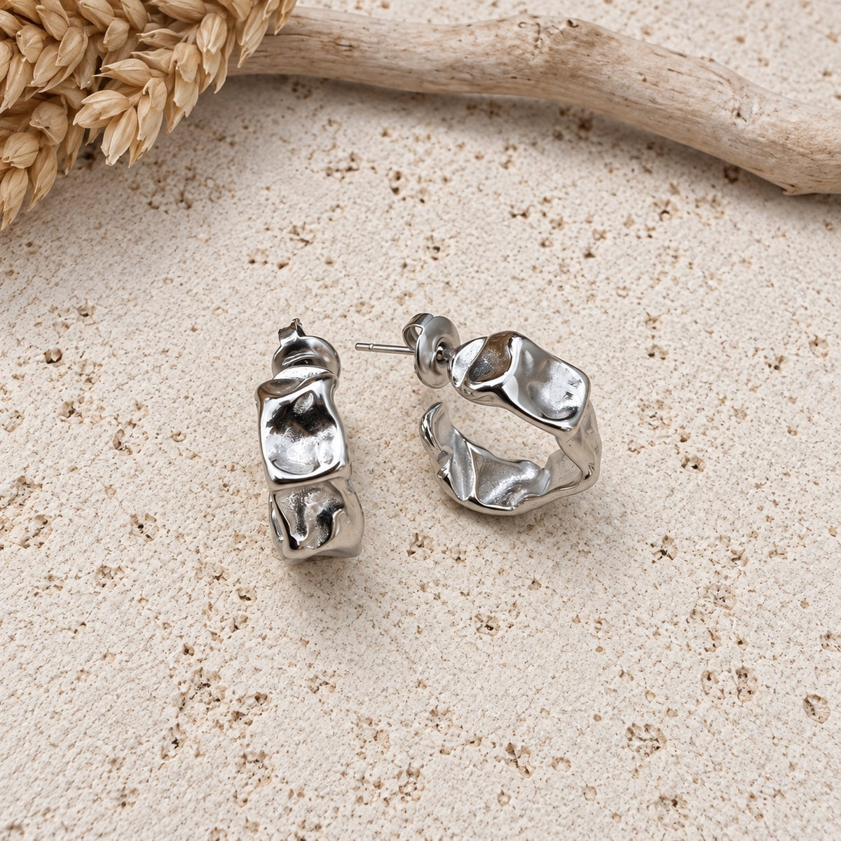 Ασημένιοι chunky C-shape κρίκοι με ανάγλυφη υφή σε travertine επιφάνεια — Celestial Steel