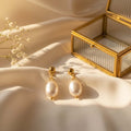 Baroque pearl drop σκουλαρίκια, χρυσό ανοξείδωτο ατσάλι με freshwater pearl, flat lay σε σατέν με glass jewelry box — Celestial Steel