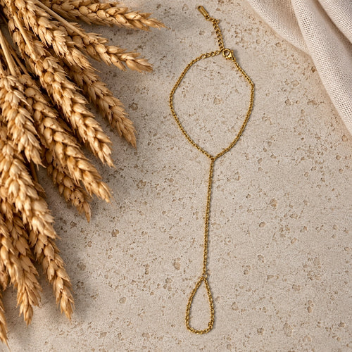 Επιχρυσωμένο hand chain σε travertine επιφάνεια — Celestial Steel
