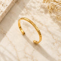 Hammered open cuff bangle βραχιόλι, χρυσό ανοξείδωτο ατσάλι, flat lay σε μάρμαρο — Celestial Steel