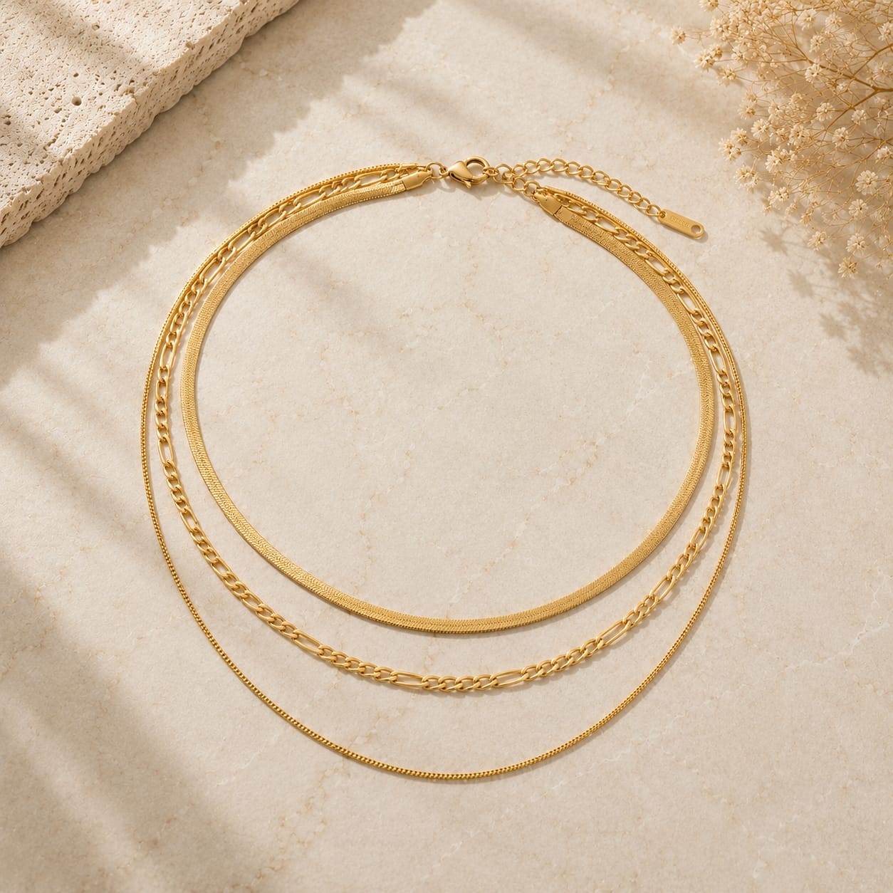 Layered 3-in-1 κολιέ herringbone, figaro και box chain, χρυσό ανοξείδωτο ατσάλι, flat lay σε μάρμαρο — Celestial Steel