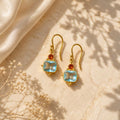 London blue topaz και rhodolite drop σκουλαρίκια, χρυσό 925 ασήμι χειροποίητο, flat lay σε μάρμαρο — Celestial Steel