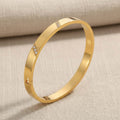 Flat cuff βραχιόλι με λευκό ζιρκόν, χρυσό ανοξείδωτο ατσάλι, flat lay σε linen — Celestial Steel