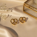 Σκουλαρίκια stud heart pretzel knot σε χρυσό ανοξείδωτο ατσάλι, lifestyle με σατέν και gypsophila — Celestial Steel 