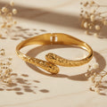 Βραχιόλι bangle hammered bypass με rounded tips, χρυσό ανοξείδωτο ατσάλι, flat lay σε μάρμαρο — Celestial Steel 