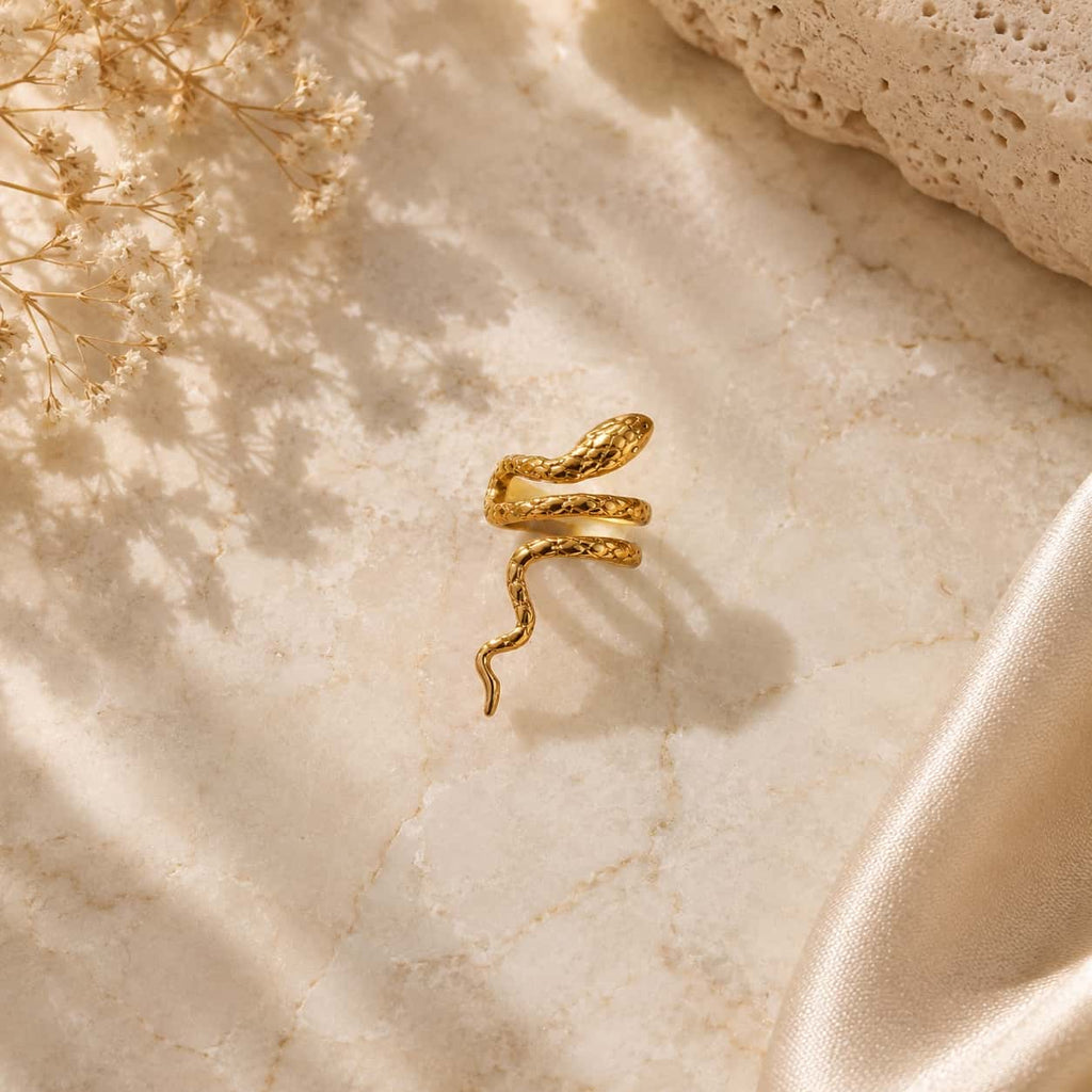 Snake ear cuff σκουλαρίκι, χρυσό ανοξείδωτο ατσάλι, flat lay σε μάρμαρο — Celestial Steel
