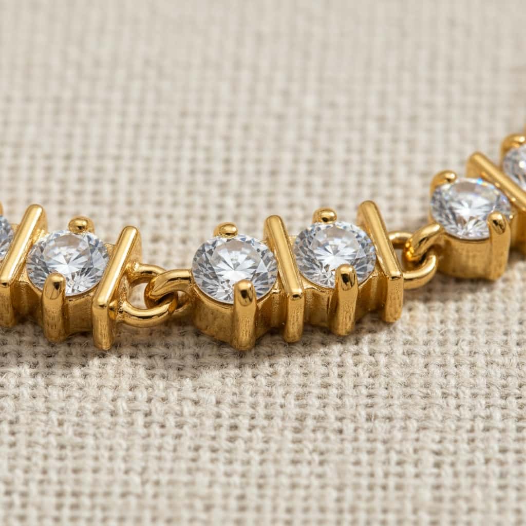 Βραχιόλι tennis round ζιργκόν σε gold X prong setting, flat lay — Celestial Steel