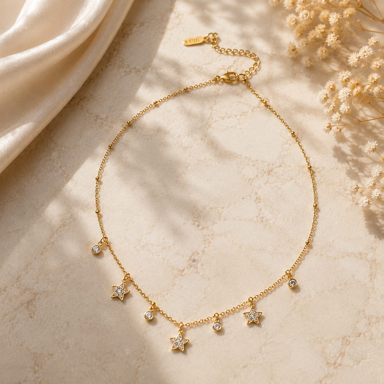 Κολιέ satellite chain με αστεράκια pave ζιργκόν και bezel-set ζιργκόν charms, χρυσό ανοξείδωτο ατσάλι, flat lay σε μάρμαρο — Celestial Steel