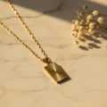 Sunburst pendant κολιέ, χρυσό ανοξείδωτο ατσάλι, flat lay σε μάρμαρο με gypsophila — Celestial Steel