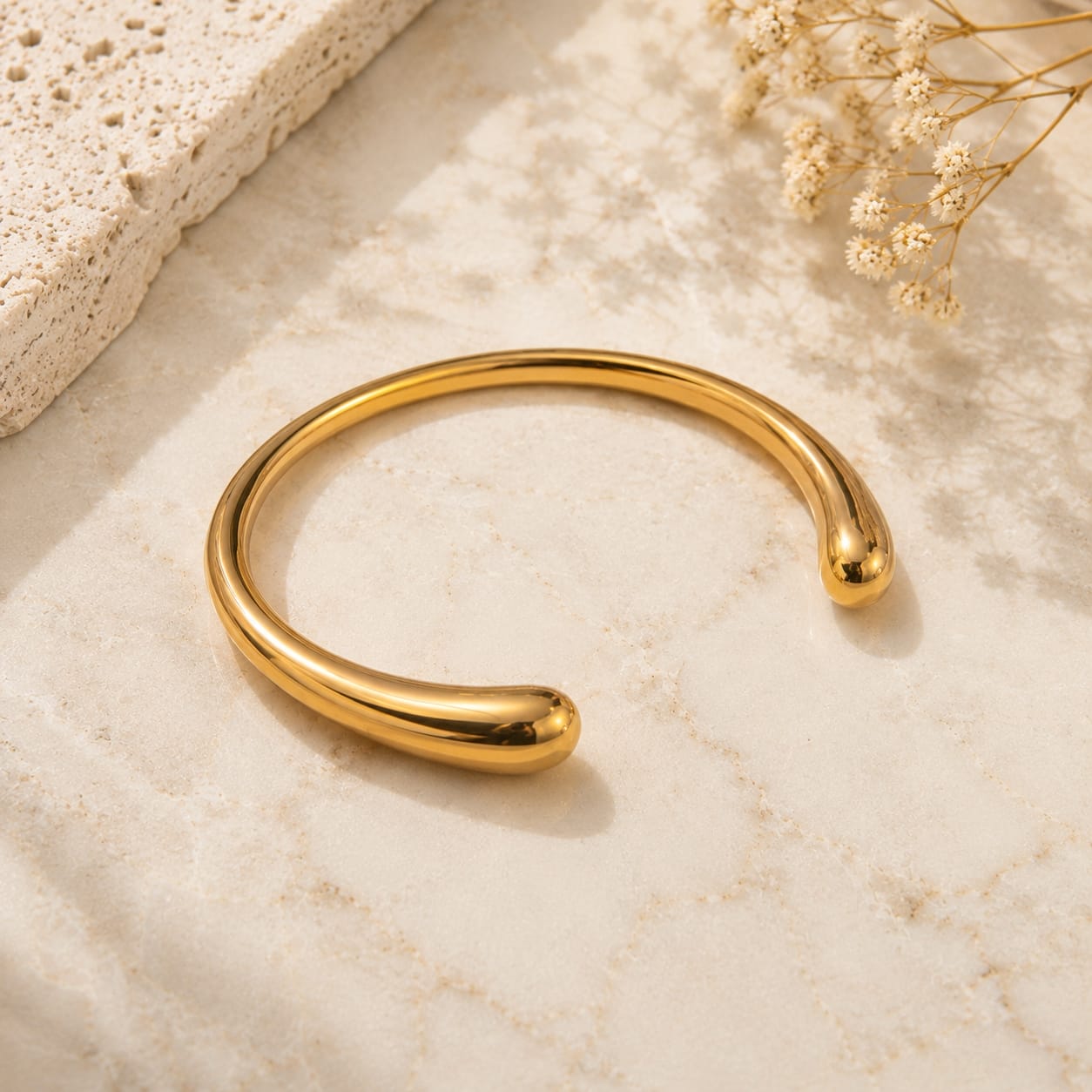 Teardrop ball end open cuff bangle βραχιόλι, χρυσό ανοξείδωτο ατσάλι, flat lay σε μάρμαρο — Celestial Steel