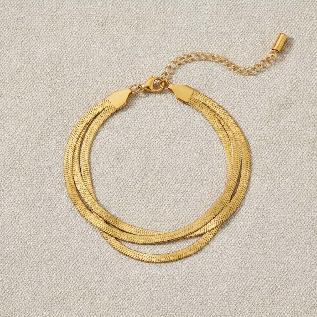Triple herringbone βραχιόλι, χρυσό ανοξείδωτο ατσάλι, flat lay σε linen — Celestial Steel