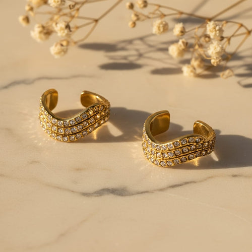 Ear cuffs τριπλή σειρά pave ζιργκόν, χρυσό ανοξείδωτο ατσάλι, flat lay σε μάρμαρο με gypsophila — Celestial Steel